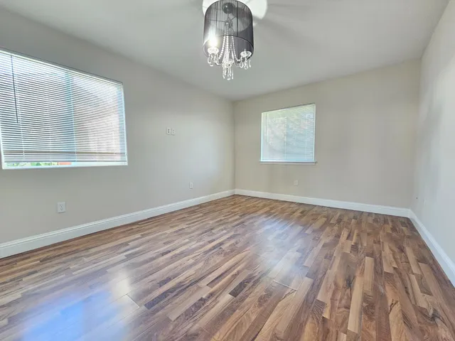 a view of a room with wooden floor a ceiling fan and windows