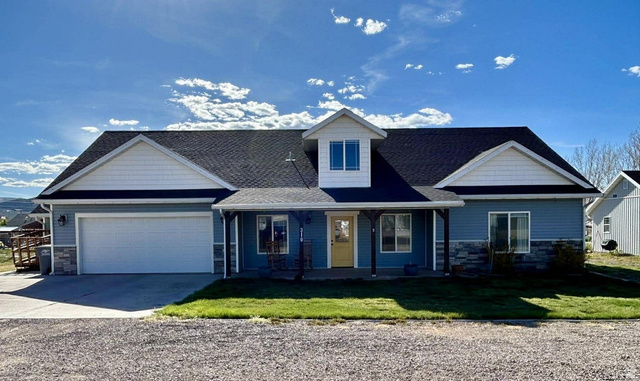 Blue siding exterior with stone accent, covered front porch, and dormer feature