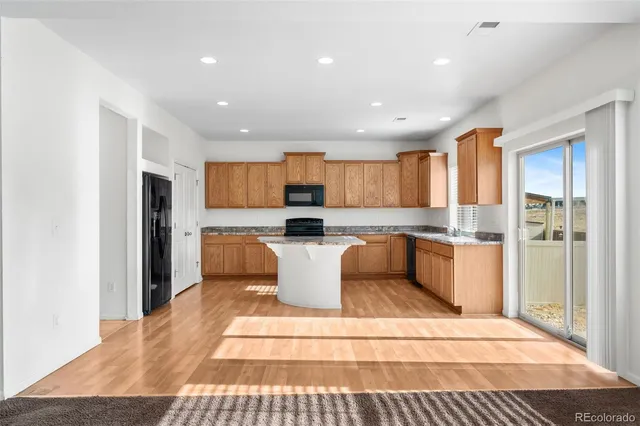 a large kitchen with stainless steel appliances kitchen island granite countertop a refrigerator and a sink