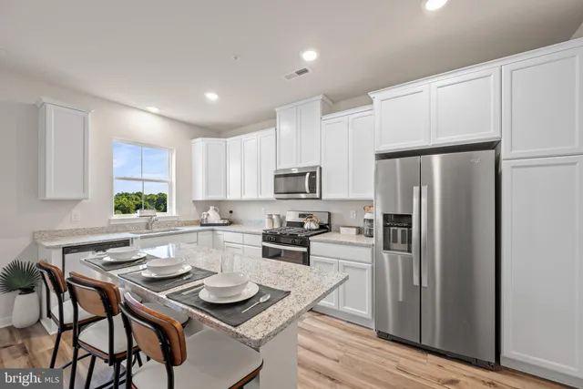 a kitchen with stainless steel appliances a stove a sink a microwave a refrigerator and cabinets