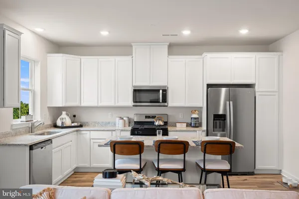 a kitchen with stainless steel appliances a stove a sink a microwave a refrigerator and cabinets