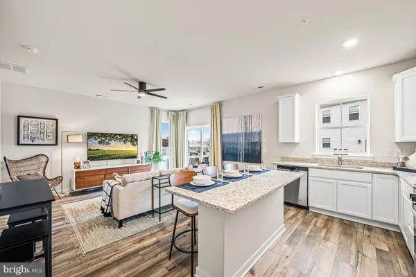 a open kitchen with stainless steel appliances granite countertop a stove top oven a sink dishwasher a dining table and chairs with wooden floor