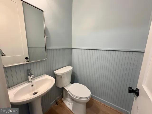 a view of a hallway with wooden floor and a bathroom