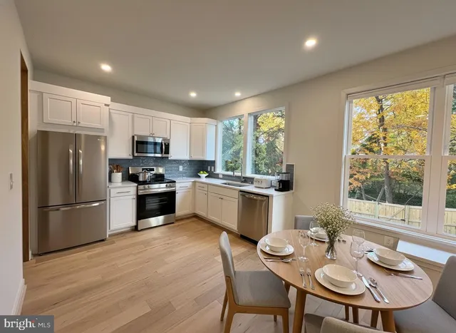 a kitchen with stainless steel appliances granite countertop a refrigerator a stove a sink dishwasher a dining table and chairs with wooden floor
