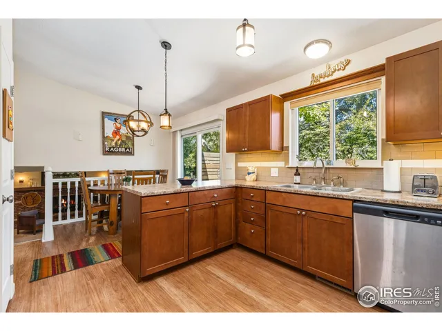 a kitchen with stainless steel appliances granite countertop a sink dishwasher a stove a microwave oven and a dining table with wooden floor