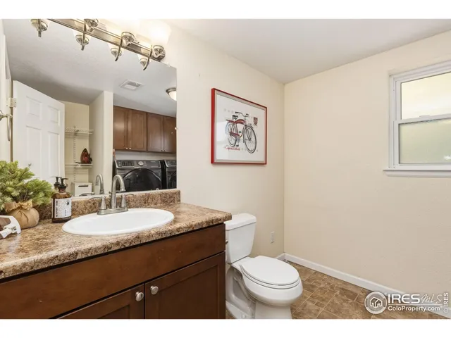 a bathroom with a granite countertop sink toilet and large mirror