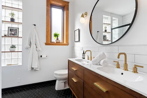 a bathroom with a sink a mirror a toilet and a window