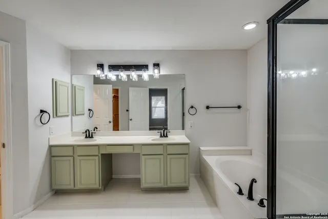 a bathroom with a double vanity sink mirror and bathtub
