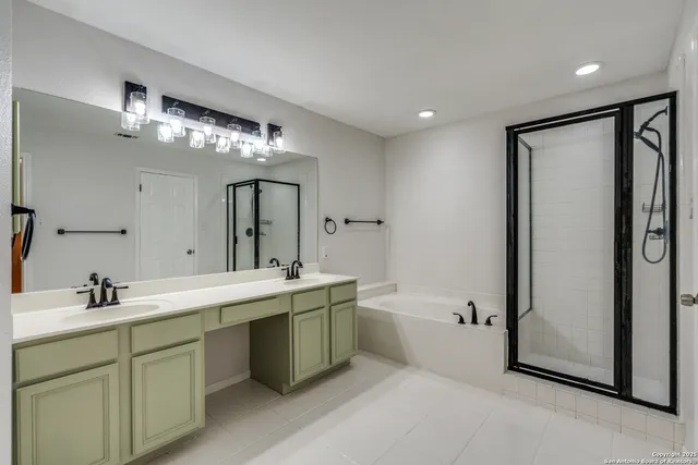 a bathroom with a double vanity sink mirror and bathtub