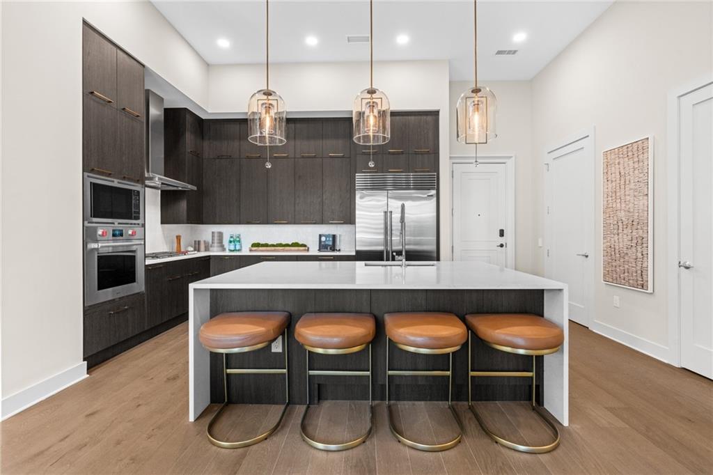 a kitchen with stainless steel appliances granite countertop a table chairs in it and wooden floors