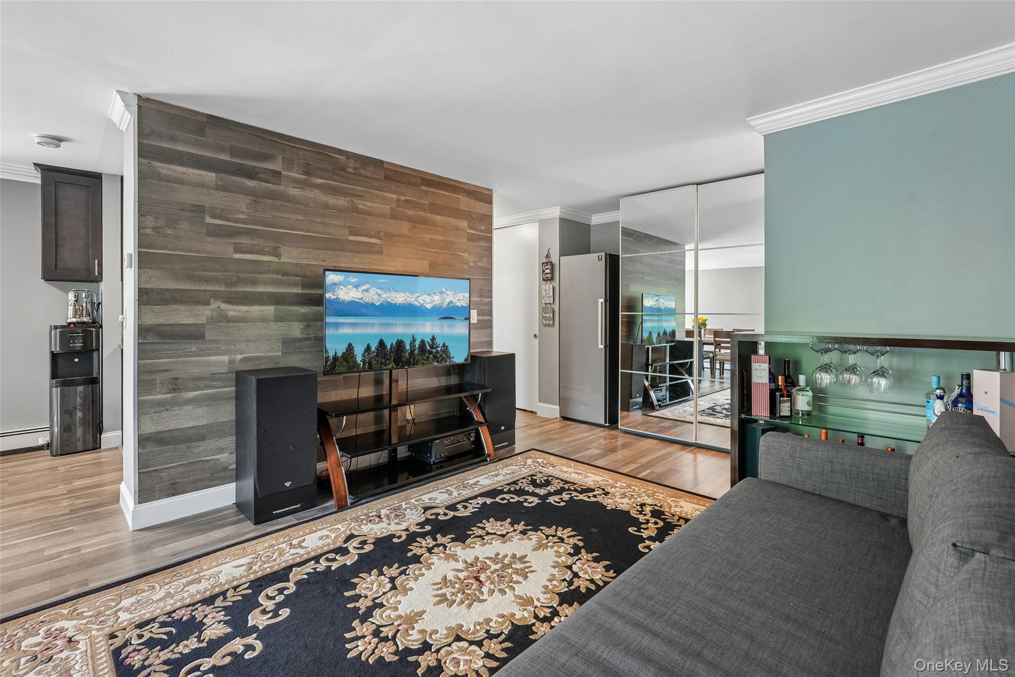 2 Secora Road, Unit C5 Monsey, NY 10952 - Photo 8 of 32 Hardwood-style flooring throughout, accent wall with horizontal wood paneling, mirrored closet doors, and a built-in bar with glass shelving