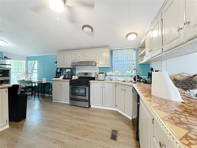 a kitchen with granite countertop a refrigerator stove top oven and cabinets