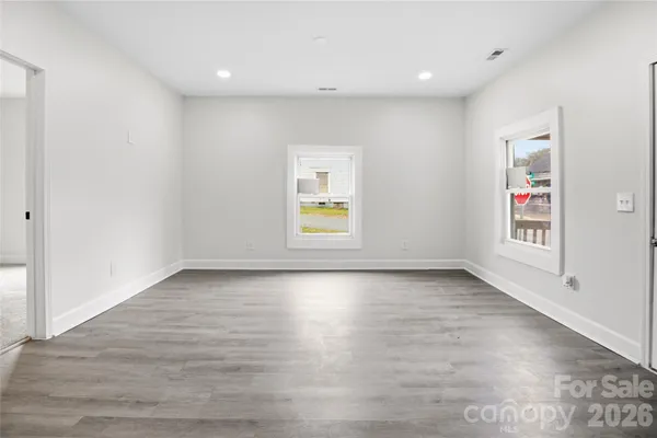 an empty room with wooden floor and windows