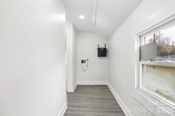a view of hallway with window and wooden floor
