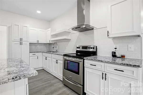 a kitchen with granite countertop stainless steel appliances sink stove and cabinets
