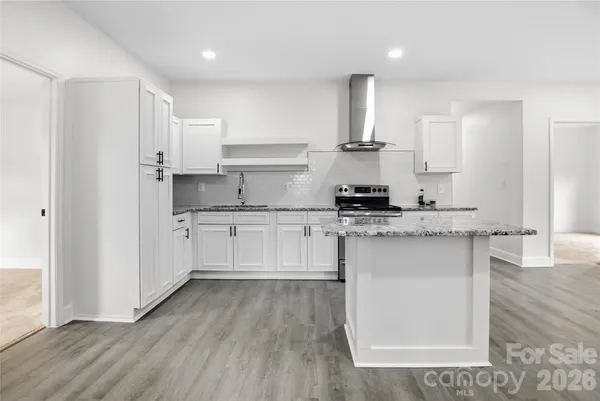 a kitchen with stainless steel appliances granite countertop a stove a sink and white cabinets