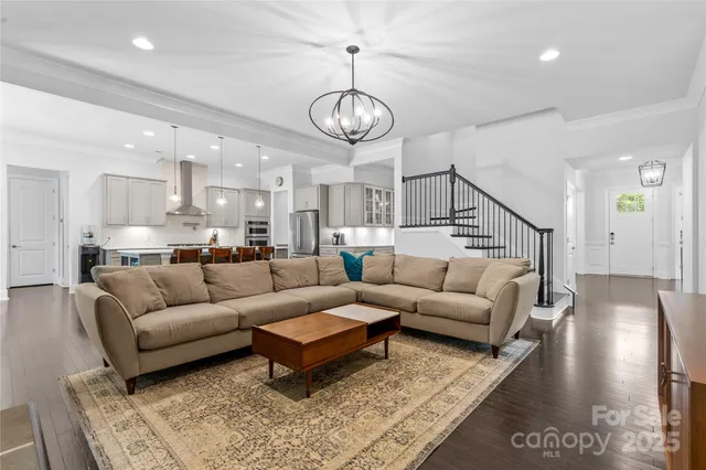 a living room with furniture a kitchen view and a chandelier