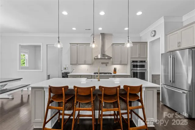 a kitchen with stainless steel appliances kitchen island granite countertop a dining table chairs and white cabinets