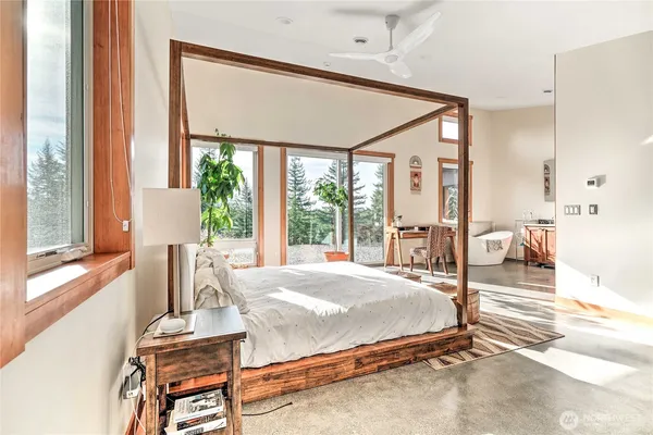 a bedroom with a bed and large windows