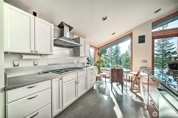 a kitchen with stainless steel appliances granite countertop a stove a sink dishwasher and white cabinets with wooden floor