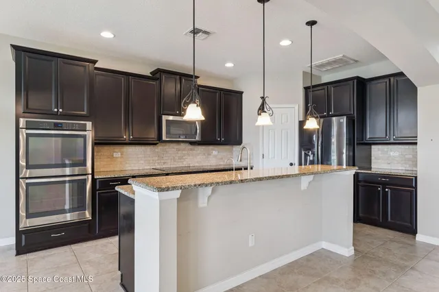 a view of an empty room with a window and kitchen view