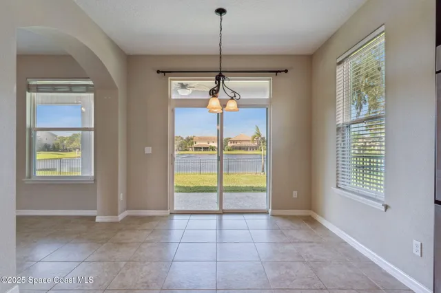a view of an empty room with kitchen and a window