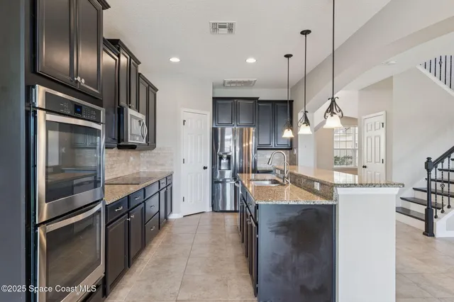 a kitchen with stainless steel appliances granite countertop a sink a stove and a refrigerator