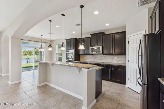 a kitchen with stainless steel appliances granite countertop a sink a stove and a wooden cabinets