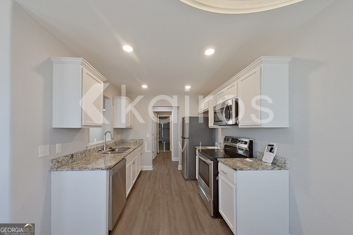 228 Western Red Cedar Drive Springfield, GA 31329 - Photo 8 of 27 a kitchen with stainless steel appliances granite countertop a stove top oven a sink a refrigerator and white cabinets with wooden floor