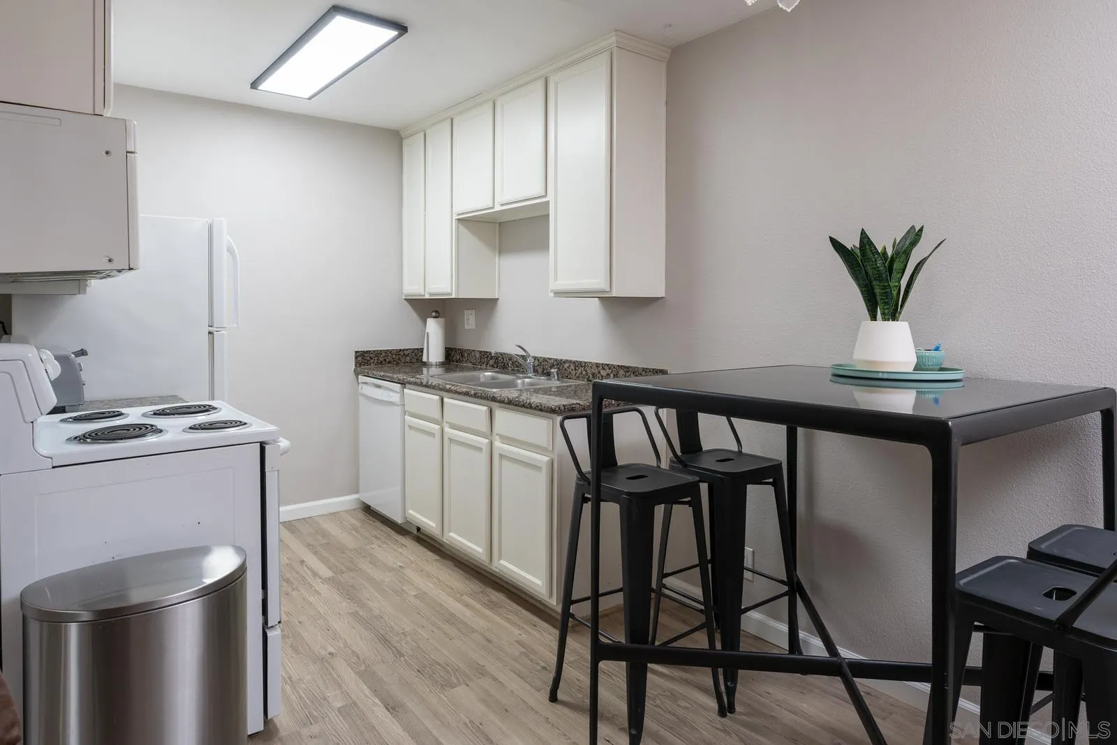 6333 Mt Ada Road, Unit 179 San Diego, CA 92111 - Photo 5 of 18 a kitchen with stainless steel appliances kitchen island a table chairs in it and wooden floors
