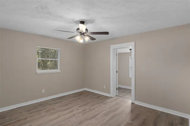 a view of an empty room with a window and wooden floor