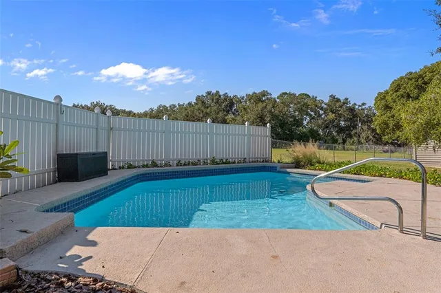 a view of a swimming pool with a lounge chair and a small yard