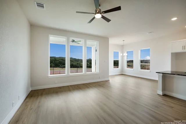 a view of a livingroom with an empty space wooden floor and a ceiling fan