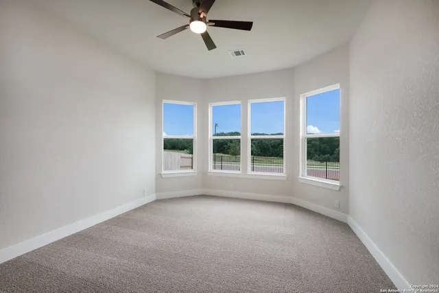 an empty room with a ceiling fan and carpet