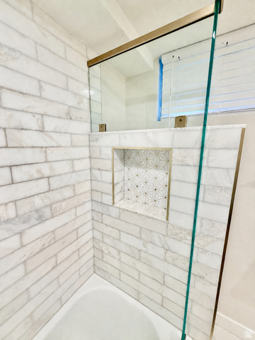 2924 Robidoux Road Sandy, UT 84093 - Photo 45 of 68 Bathtub with subway tile surround, integrated shower niche with decorative tile, and glass shower enclosure with brass-finish hardware