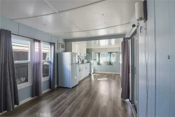 a view of a hallway with wooden floor and a kitchen