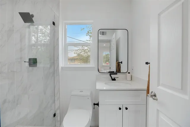 a bathroom with a sink vanity mirror and toilet