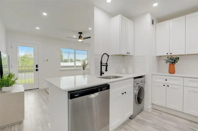 a kitchen with white cabinets and sink