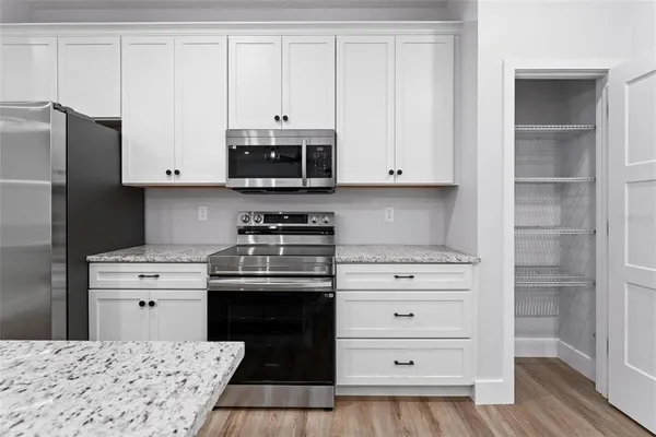 a kitchen with granite countertop white cabinets and stainless steel appliances