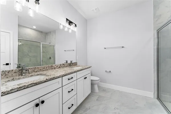 a bathroom with a granite countertop sink a toilet and a mirror