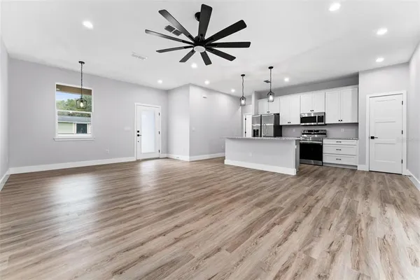 an open kitchen with wooden floors and stainless steel appliances