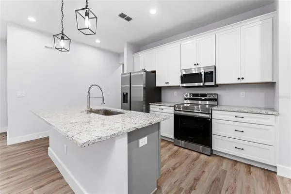a kitchen with stainless steel appliances granite countertop a sink dishwasher a stove and a refrigerator