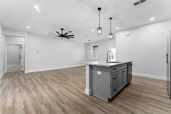 a kitchen with stainless steel appliances granite countertop a sink a stove and a wooden floor