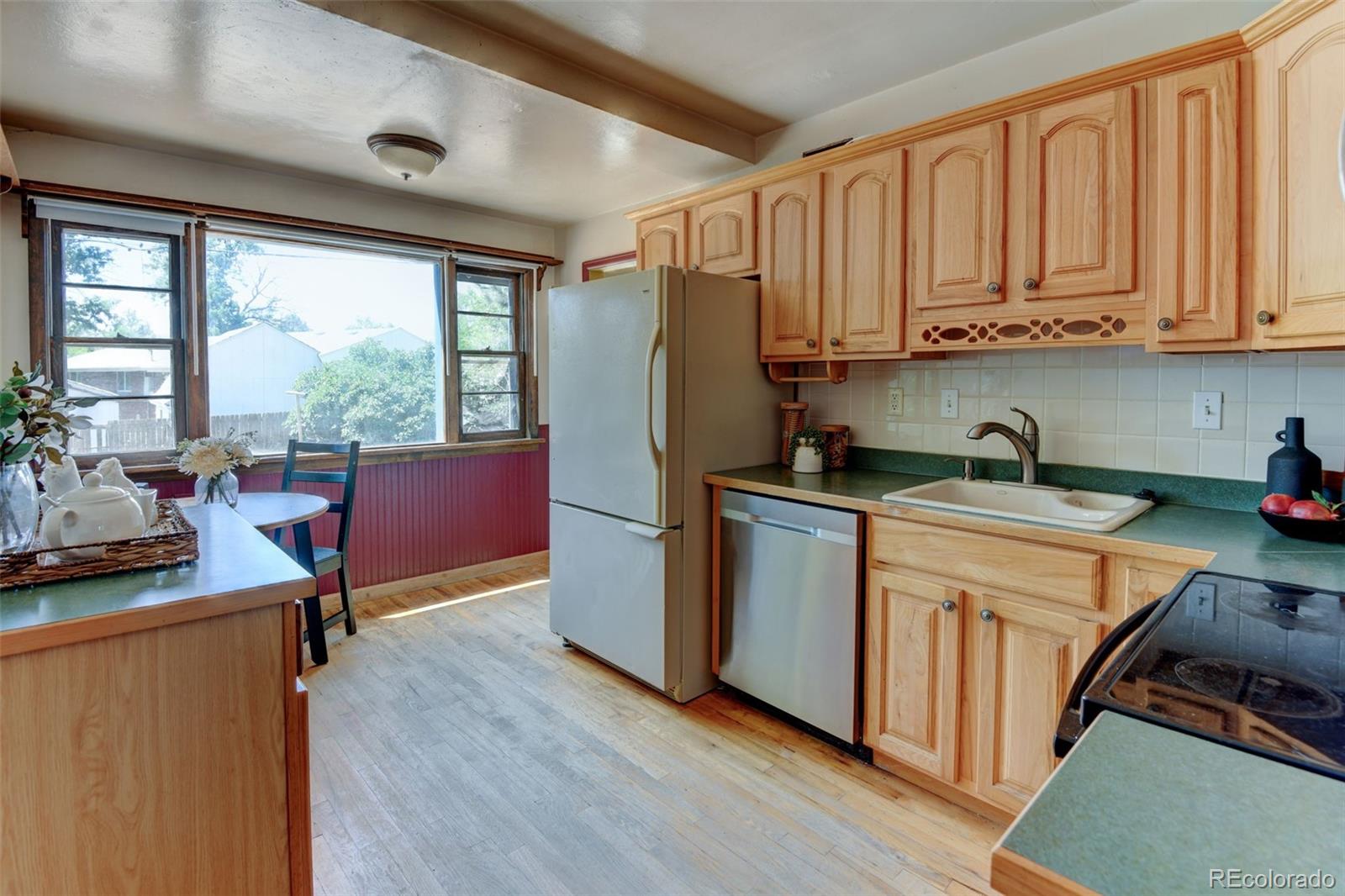 6788 Pierce Way Arvada, CO 80003 - Photo 13 of 28 a kitchen with stainless steel appliances granite countertop a refrigerator a sink dishwasher a stove and white countertops with wooden floor