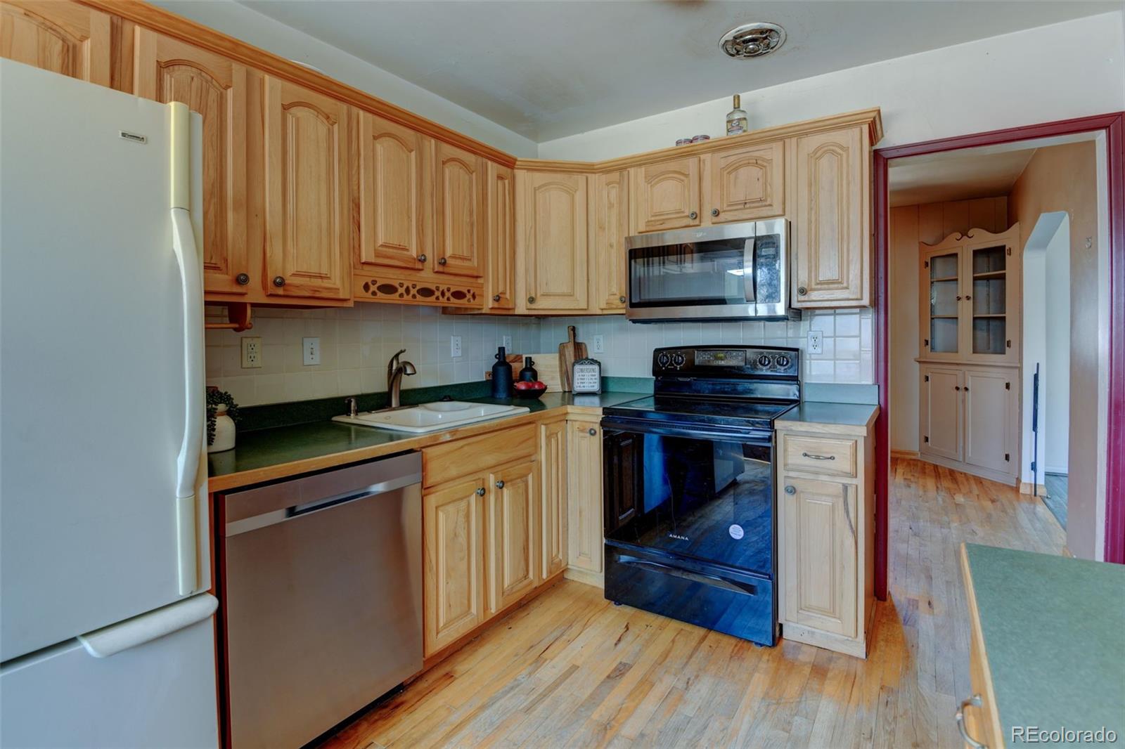 6788 Pierce Way Arvada, CO 80003 - Photo 15 of 28 a kitchen with stainless steel appliances granite countertop wooden cabinets a stove a sink and a microwave