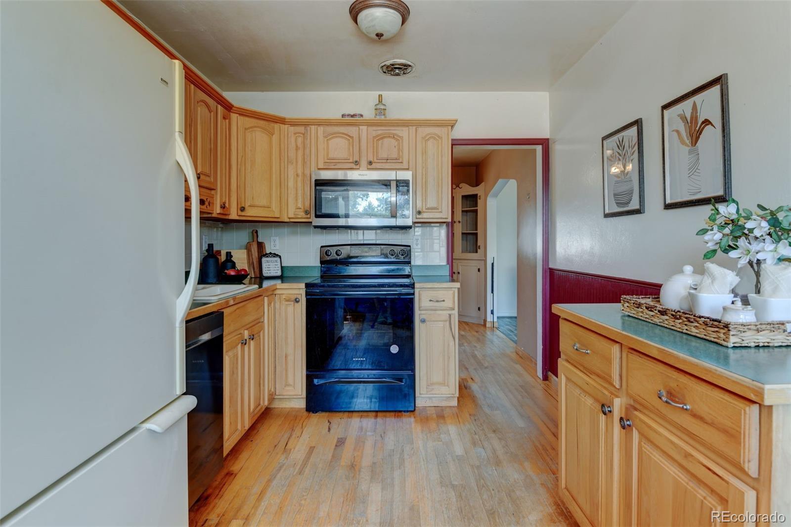 6788 Pierce Way Arvada, CO 80003 - Photo 16 of 28 a kitchen with stainless steel appliances granite countertop a refrigerator a stove top oven a sink dishwasher and wooden floor