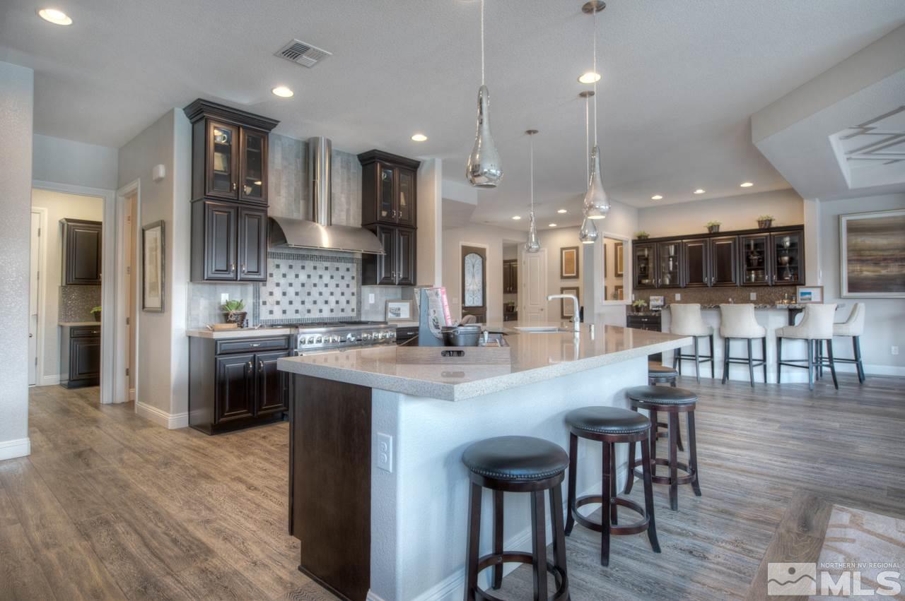 2095 Altair Lane, Unit MESSINA MODEL LOT 32 Reno, NV 89521 - Photo 8 of 25 a kitchen with stainless steel appliances kitchen island granite countertop a table chairs sink and cabinets