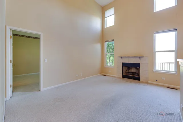 an empty room with windows and fireplace