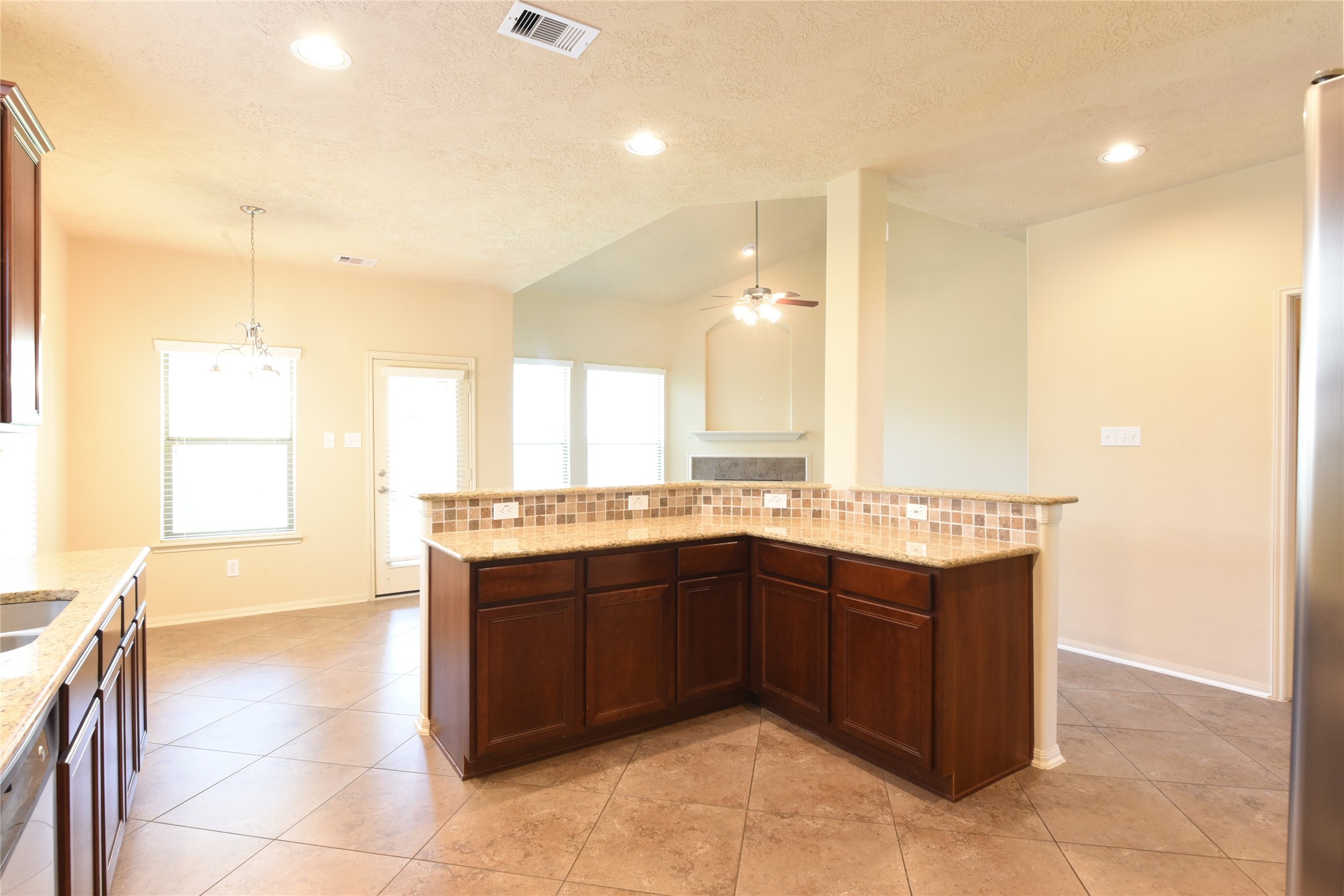 118 East Lasting Spring Circle Spring, TX 77389 - Photo 11 of 46 Spacious kitchen with elegant dark wood cabinetry, a stylish tile backsplash, and an open layout leading to a cozy living area with a ceiling fan.