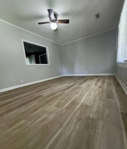 an empty room with wooden floor and windows